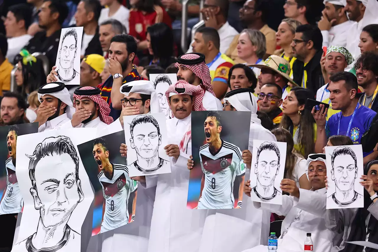 Fans hold pictures of Ozil while covering mouths during Germany World Cup match