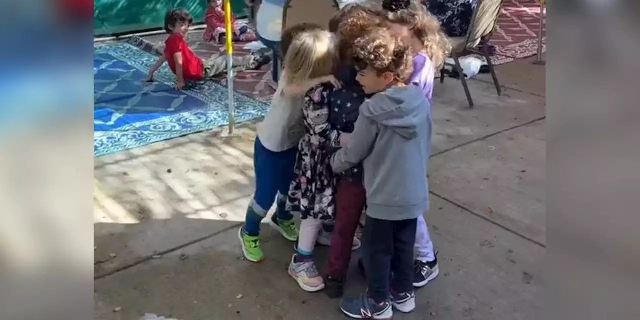 Little boy gets big group hug from friends while twin brother remains in hospital