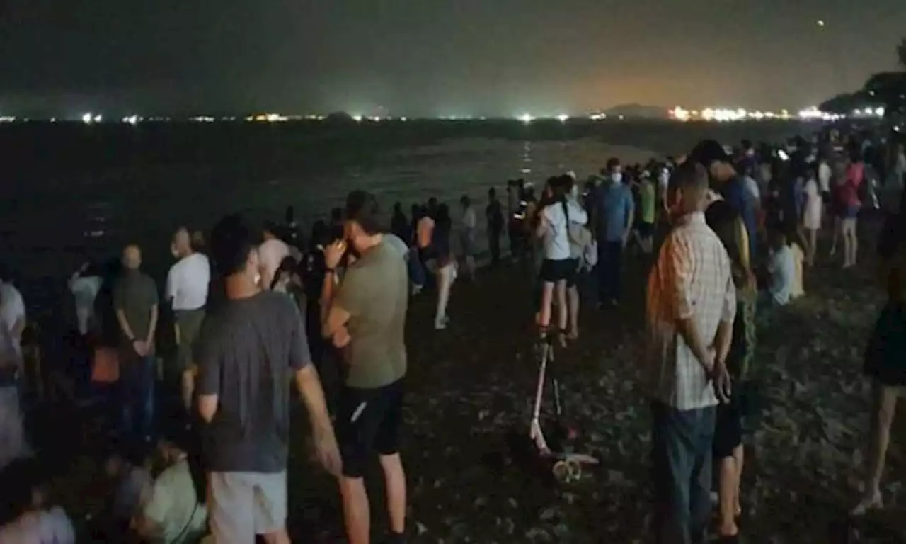 Singaporeans throw trash into the sea to trigger blue waves at Changi Beach