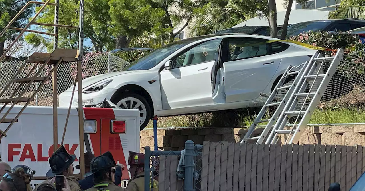 Tesla crashes through fence, lands perched on edge of ambulance in San Diego