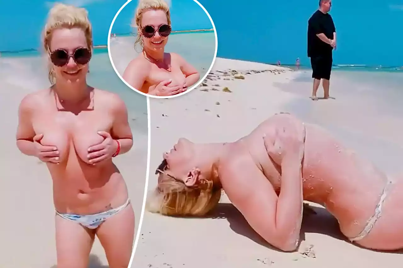 Britney Spears rolls around topless in the sand on vacation