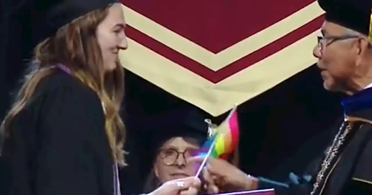 Graduating students hand school president rainbow flags in protest of anti-LGBTQ staff policies