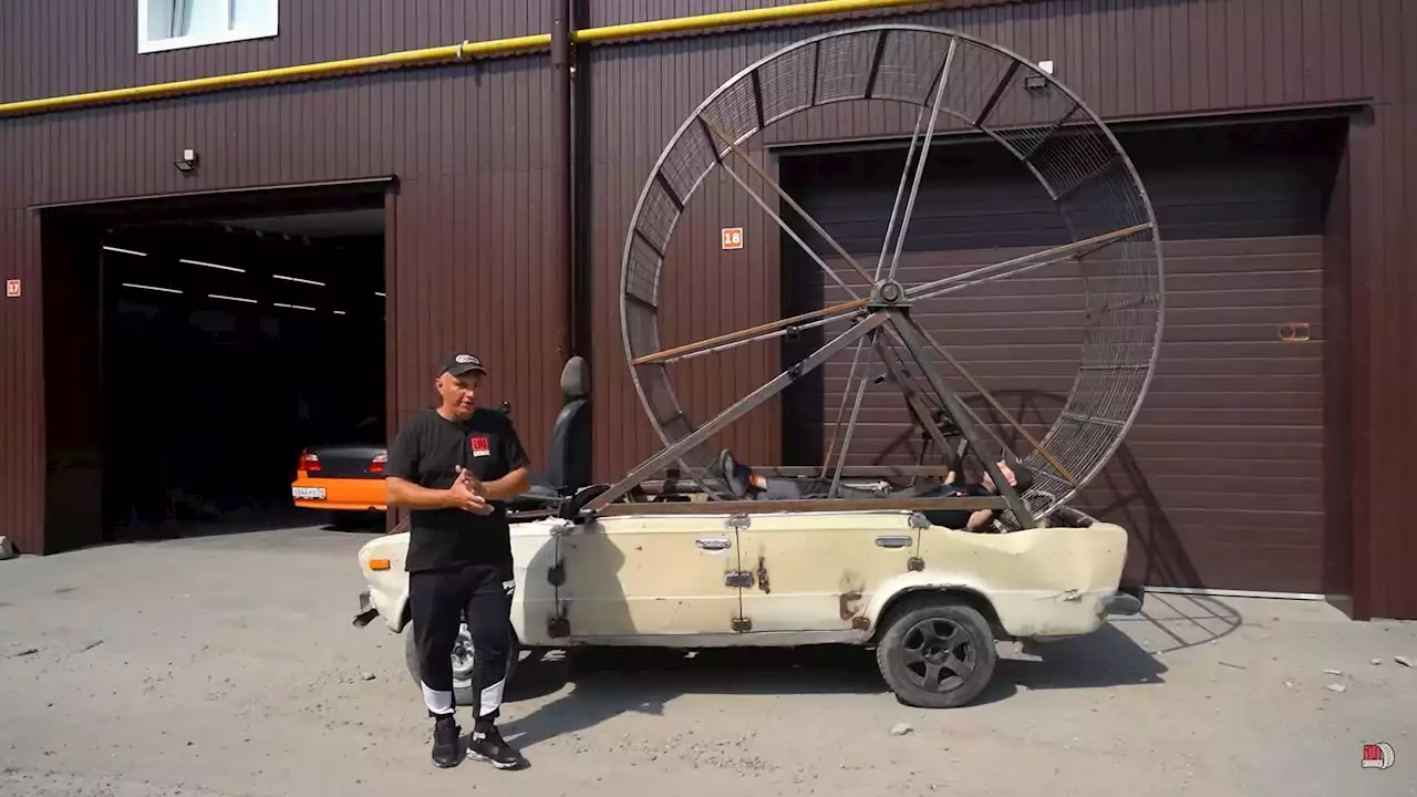 Mechanics ride a car using a giant hamster wheel