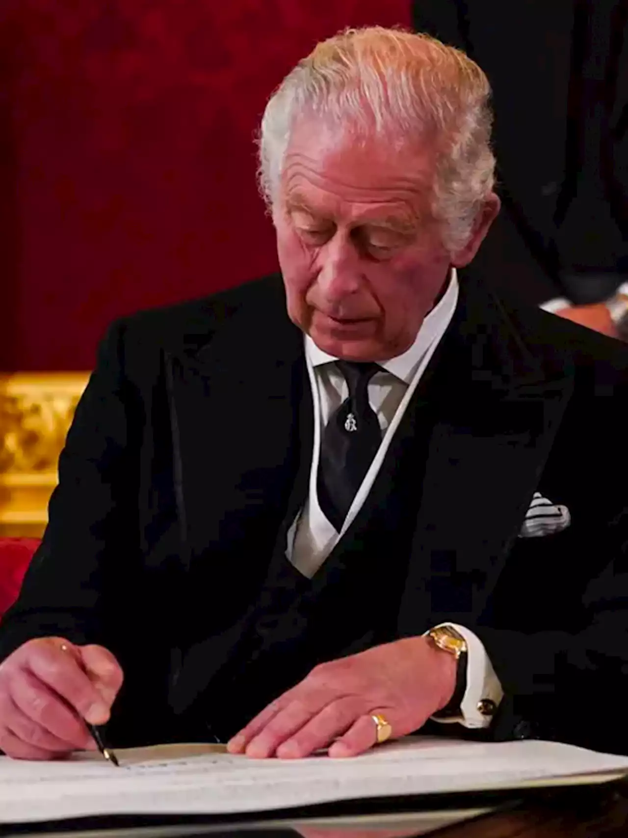 King Charles III furiously signaling aides to clear desk