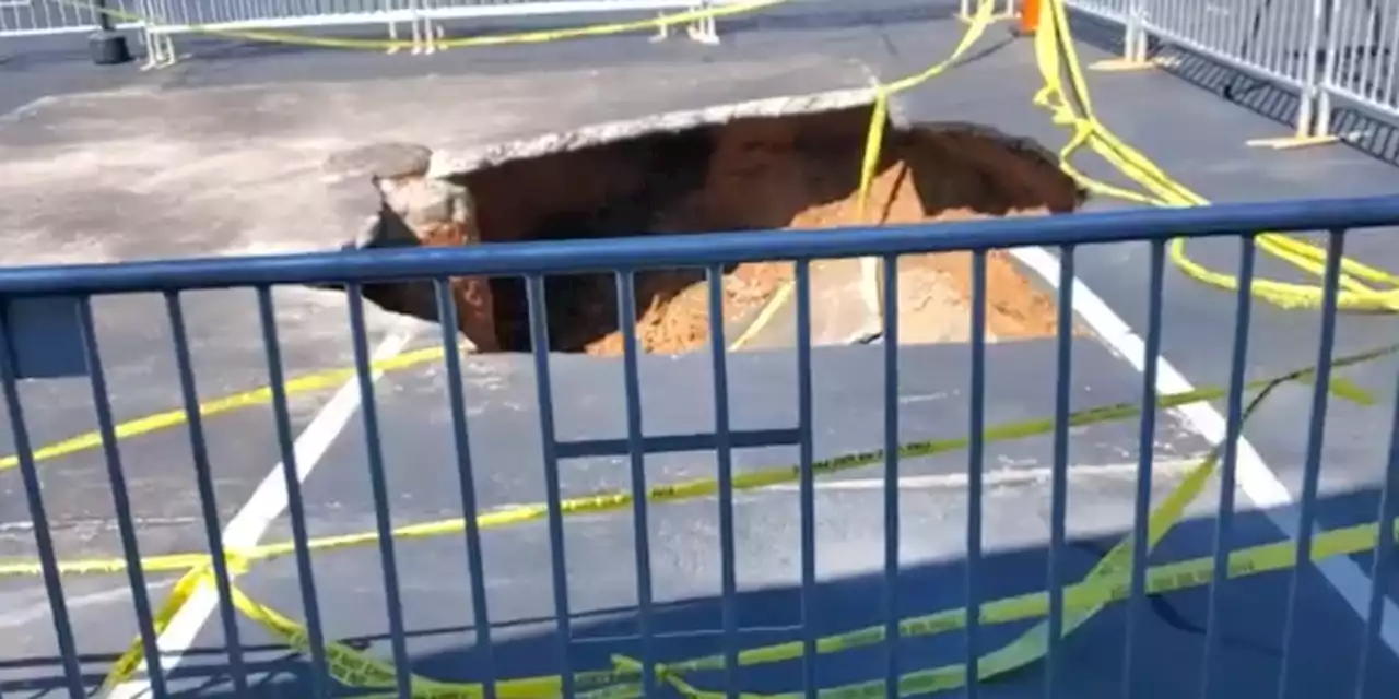 Woman falls into massive sinkhole at a car dealership