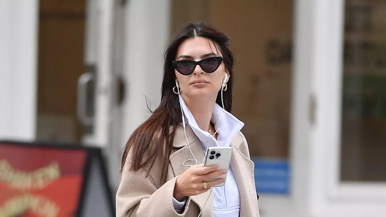 Emily Ratajkowski layers up in a chic beige coat and white sweat pants during stroll in New York...