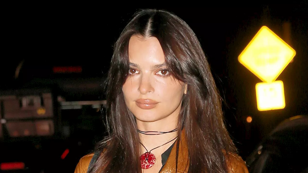 Emily Ratajkowski shows off her fall style wearing a brown leather trench coat and suede boots...