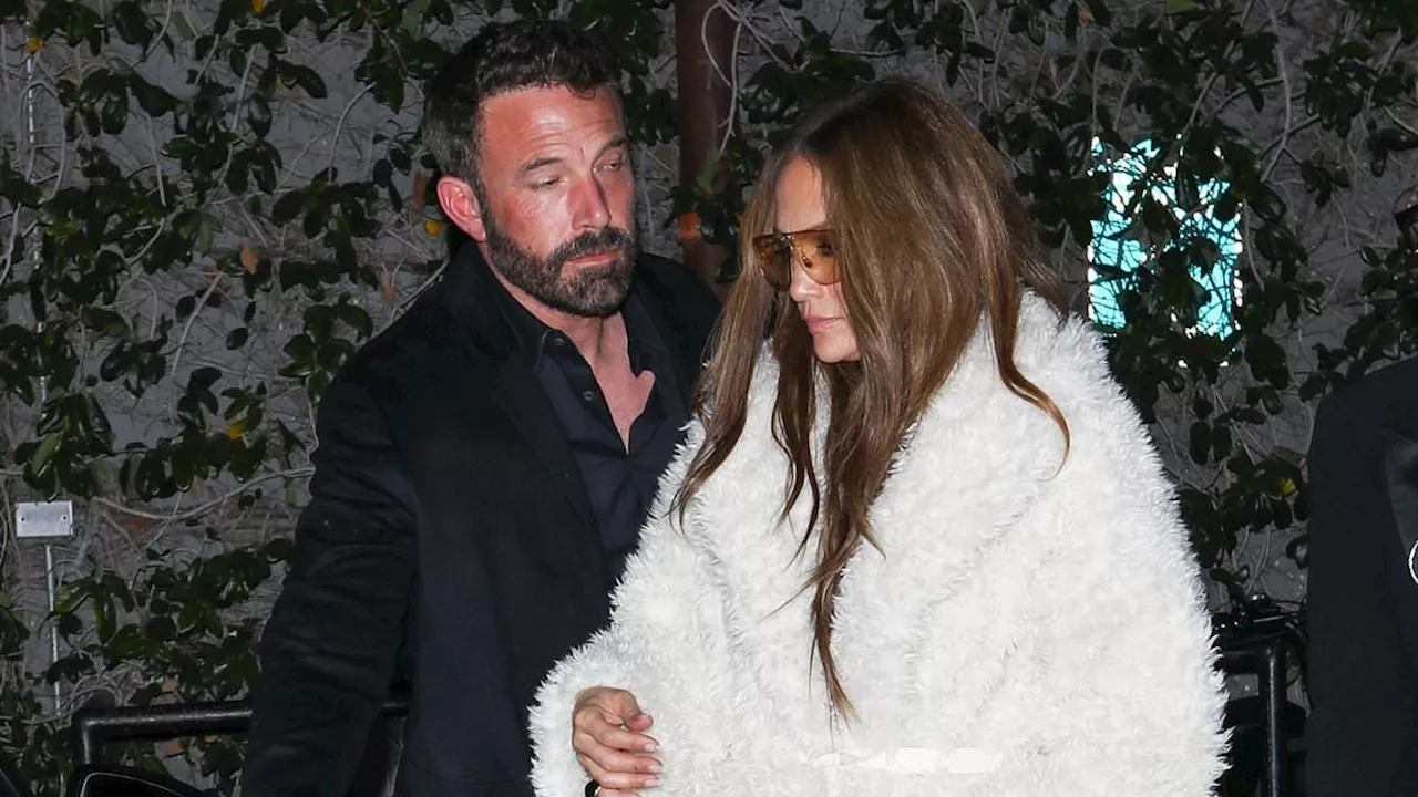 Jennifer Lopez models a large fuzzy coat as husband Ben Affleck opens the car door for her while...