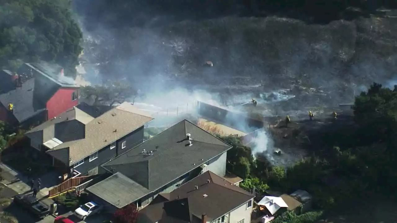 Residence's attic on fire in East Oakland as crews battle grass fire