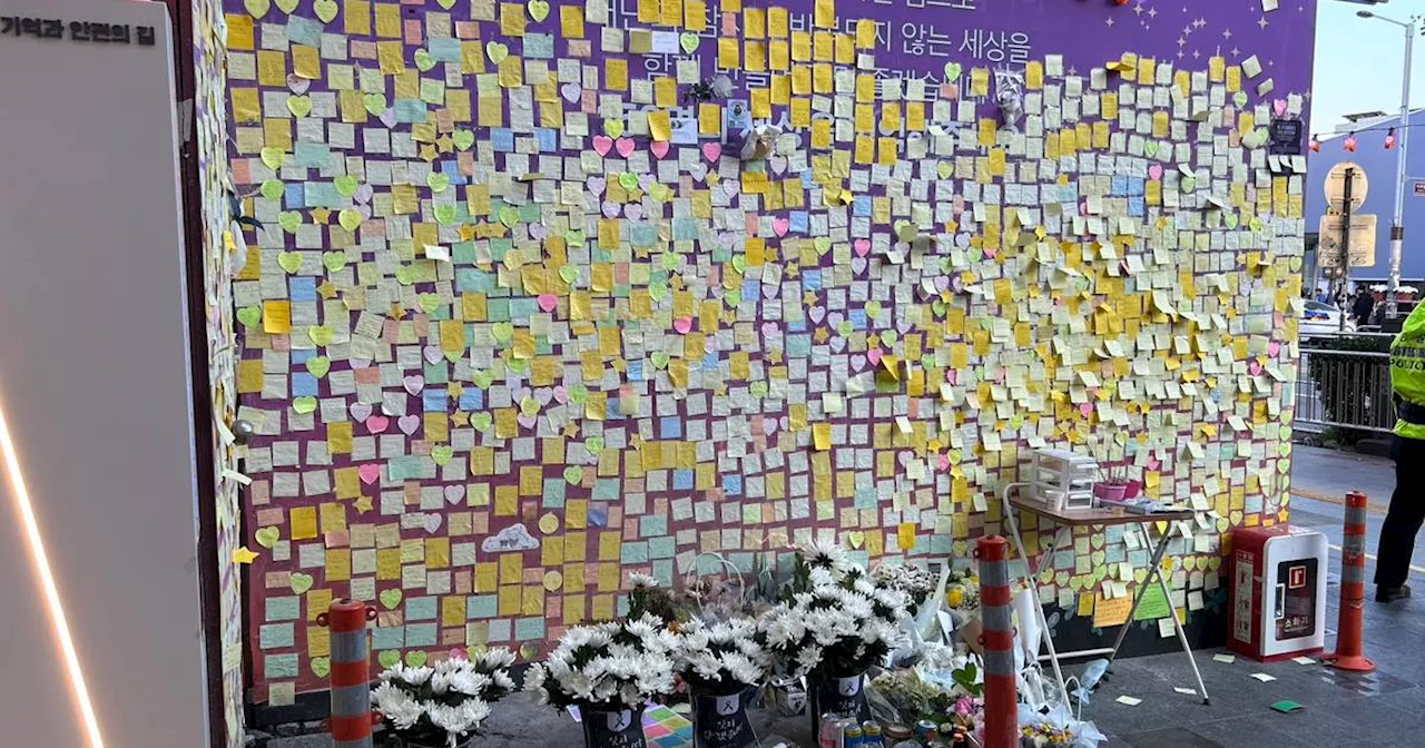 People place flowers at memorial wall in Seoul on anniversary of Halloween stampede