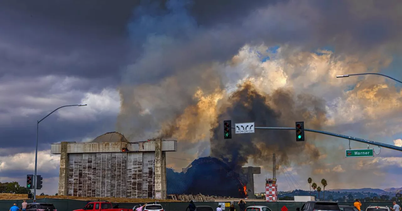 Fire burning what's left of Tustin hangar could stall abatement. Schools remain closed