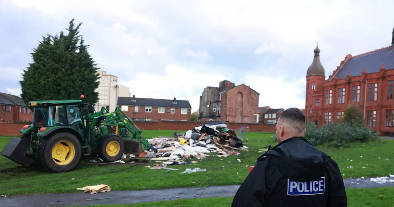 Huge bonfire is pulled down by council as police watch on