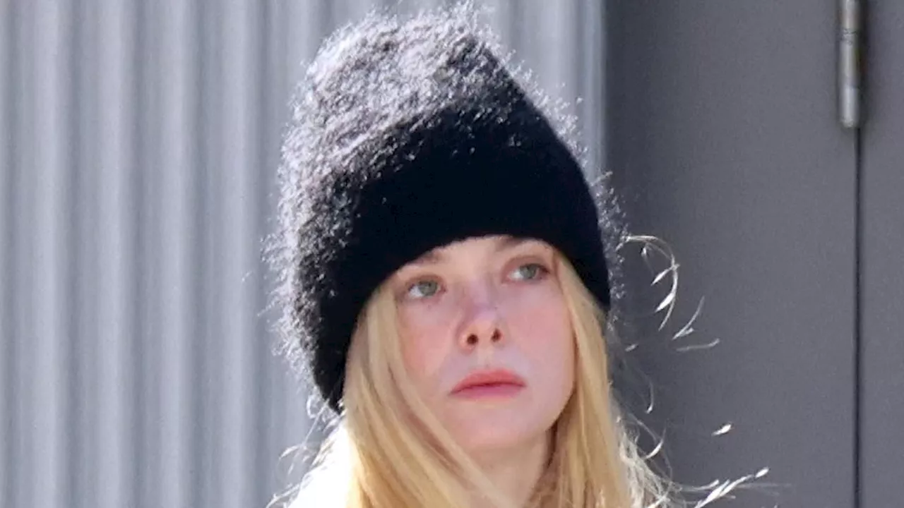 Elle Fanning wraps up warm in a black coat and matching beanie hat as she goes for a stroll in NYC...