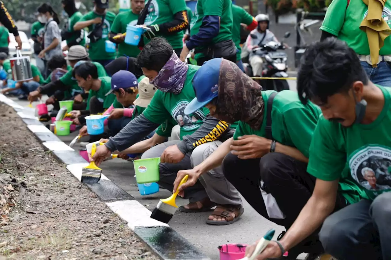 Komunitas Ojol Dukung Ganjar Mengecat Separator Jalan di Cibinong