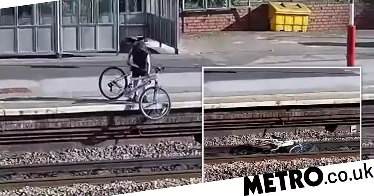 Moment two youths throw a bike onto a busy railway track