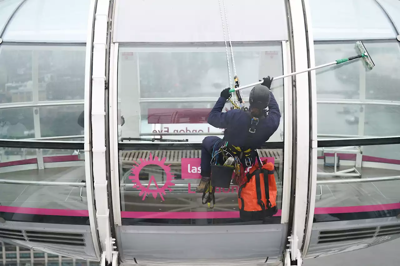 Cleaner dangles off the London Eye to give the landmark a Spring clean