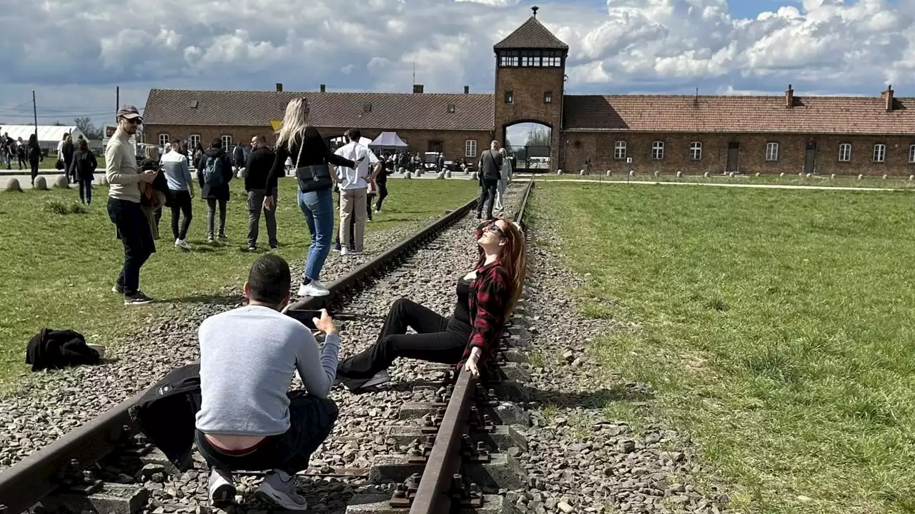 La foto della ragazza in posa e sorridente davanti ad Auschwitz