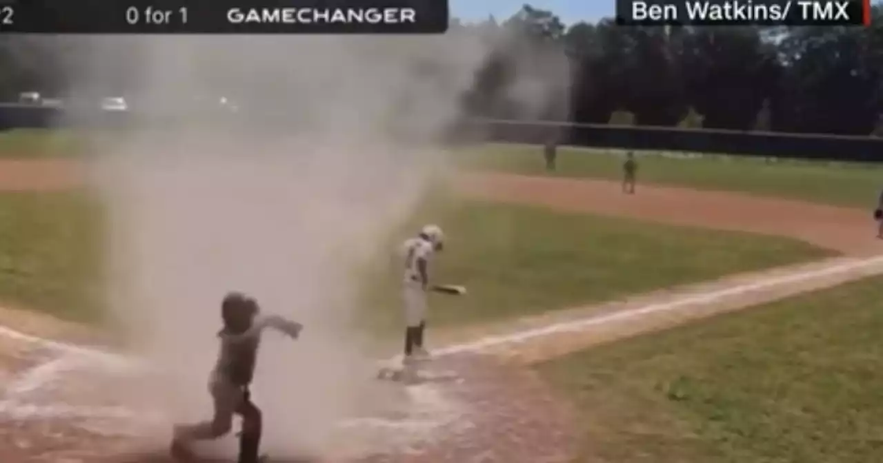 Umpire saves young boy on field as dust devil engulfs him