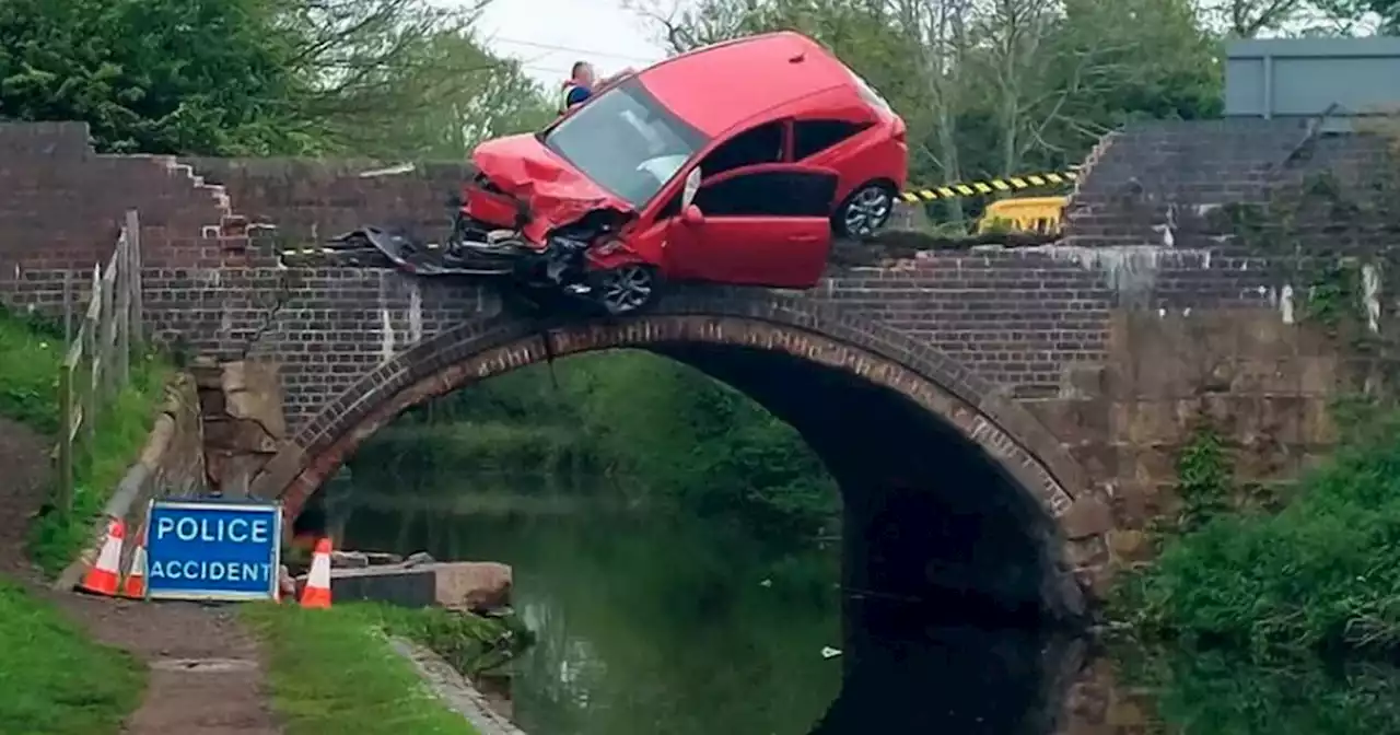 Car left dangling over bridge as passenger jumps from vehicle in to canal