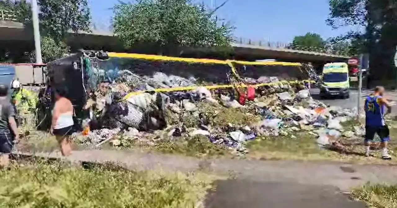 Live as truck 'tips over' and strews rubbish on busy roundabout