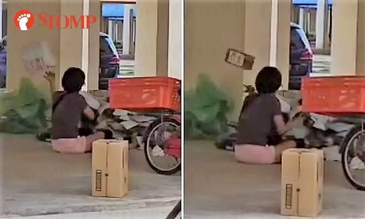 Woman sits in Tampines void deck and sorts parcels by tossing them around