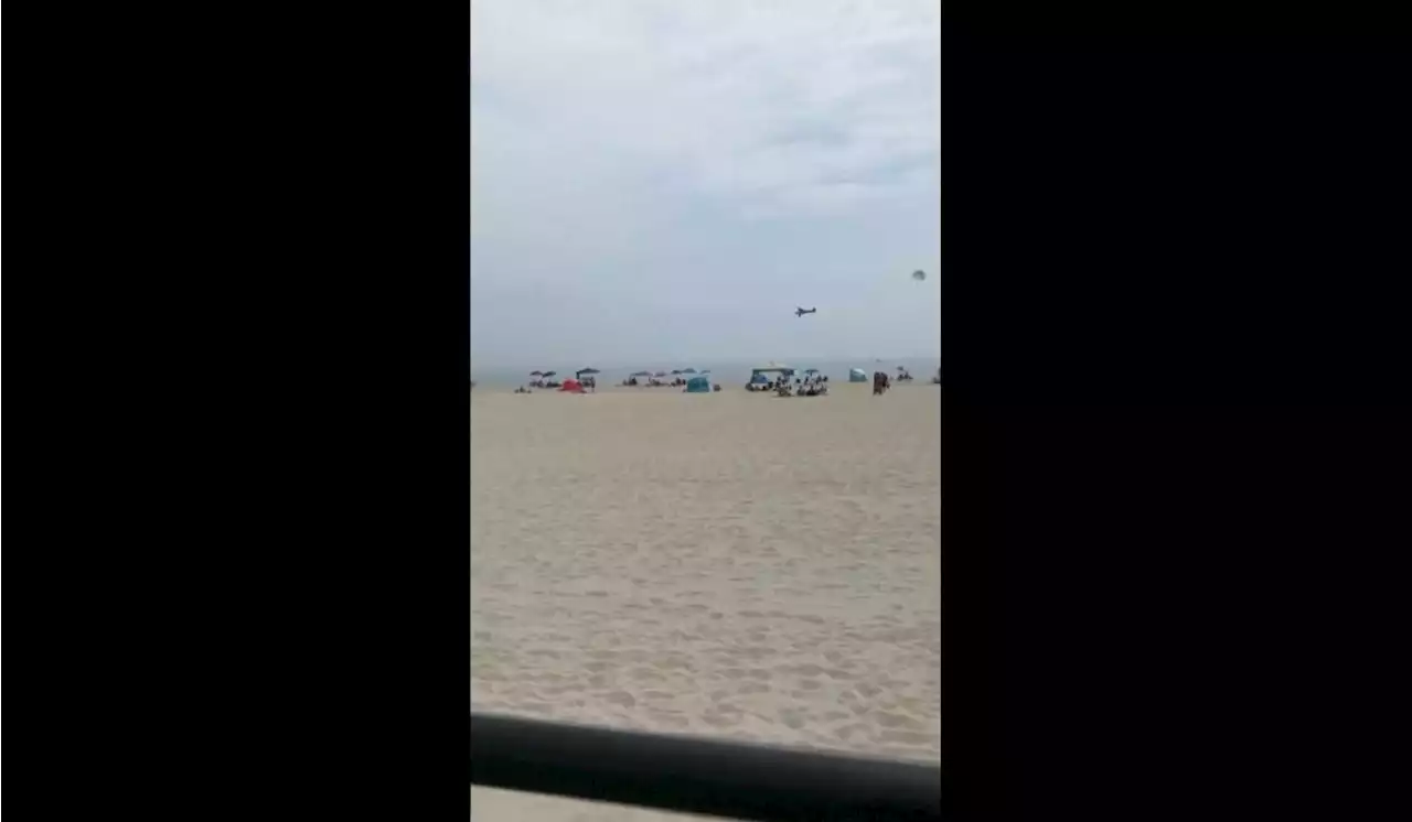 A plane towing a banner lands in the ocean off a crowded New Hampshire beach