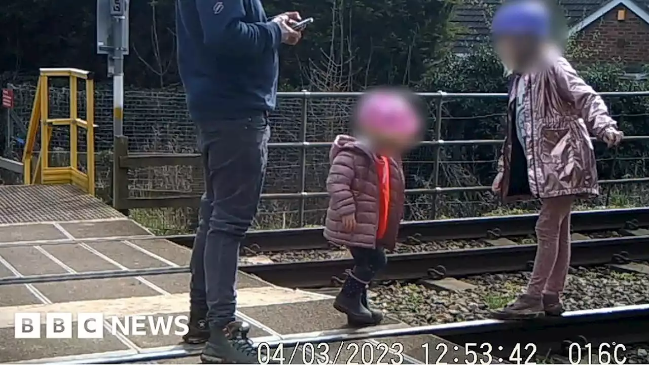 Watch: Children play on railway tracks as man looks at phone