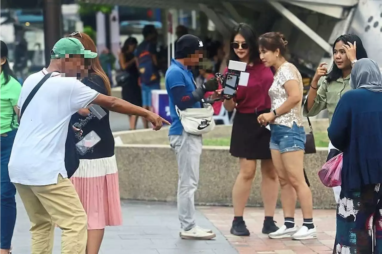 Touts around Kuala Lumpur City Centre pester tourists to have paid shots taken