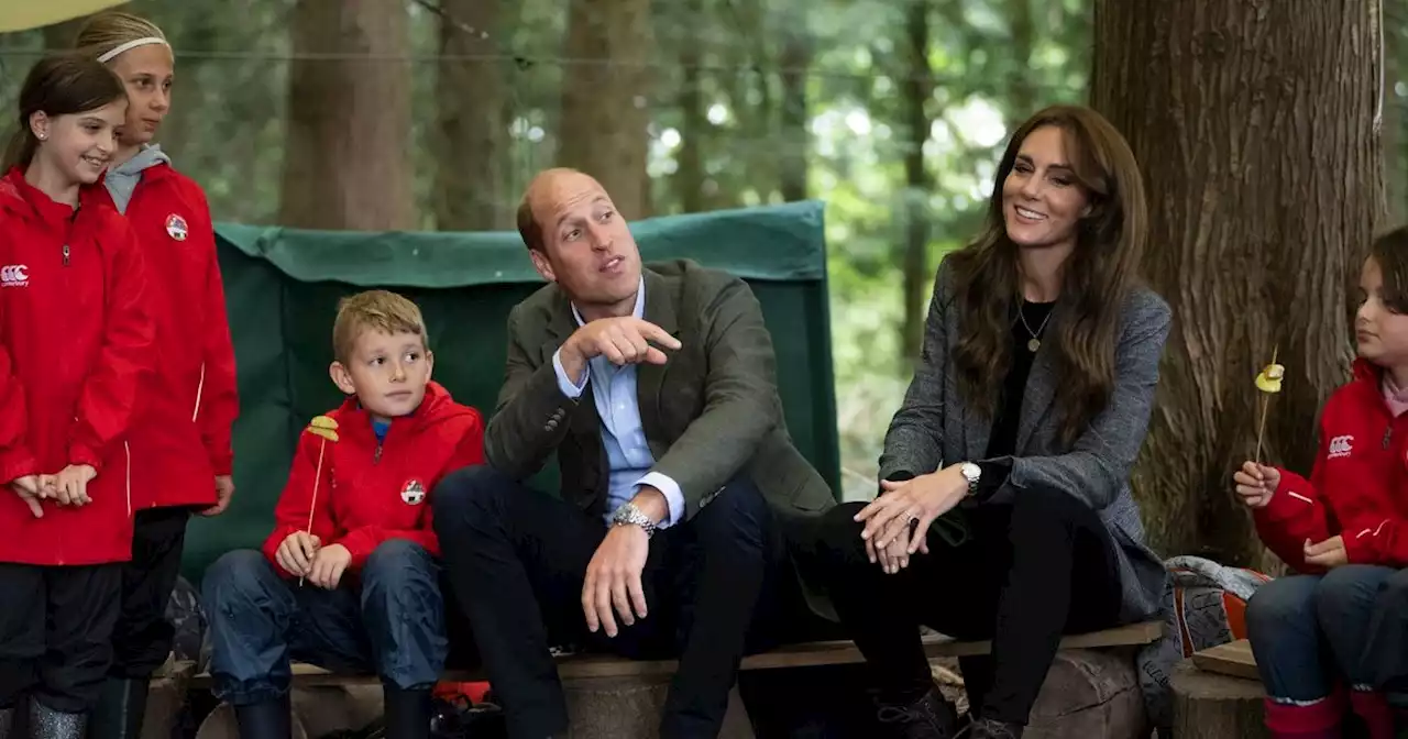 Kate and William are happy campers and help kids prepare food around campfire