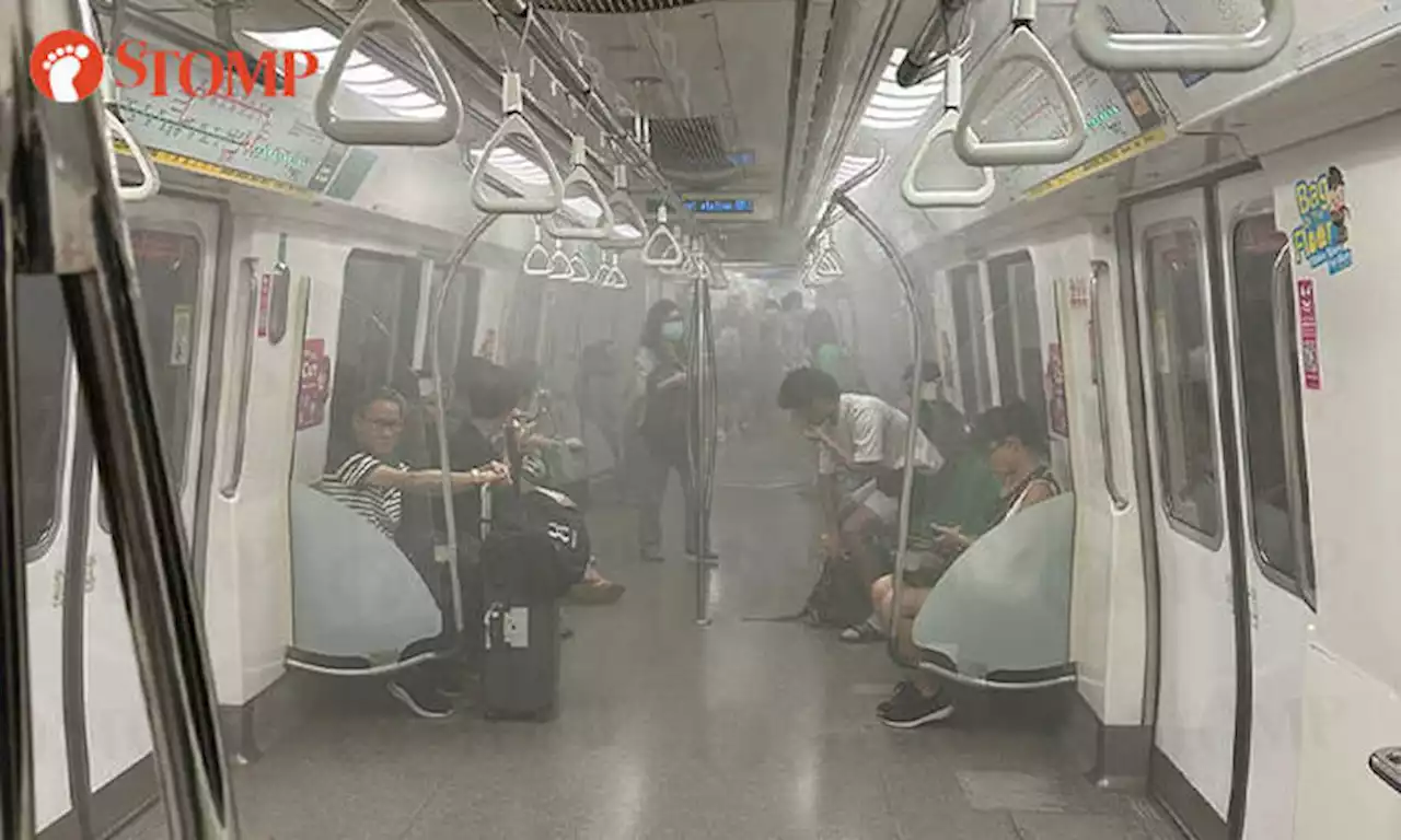 Passengers stream out of train at City Hall MRT Station after white smoke fills cabin