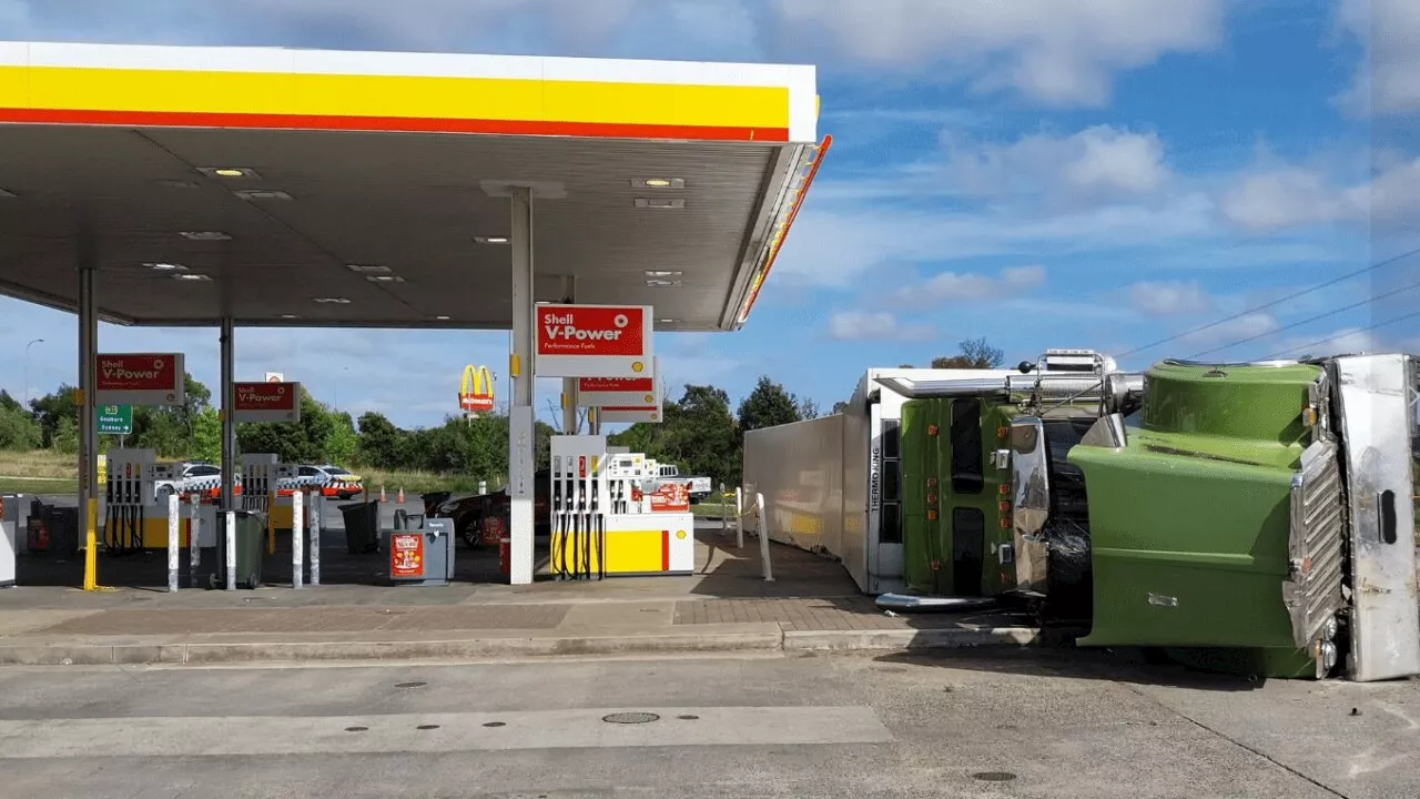 Shock as enormous truck tips over, narrowly misses petrol bowsers