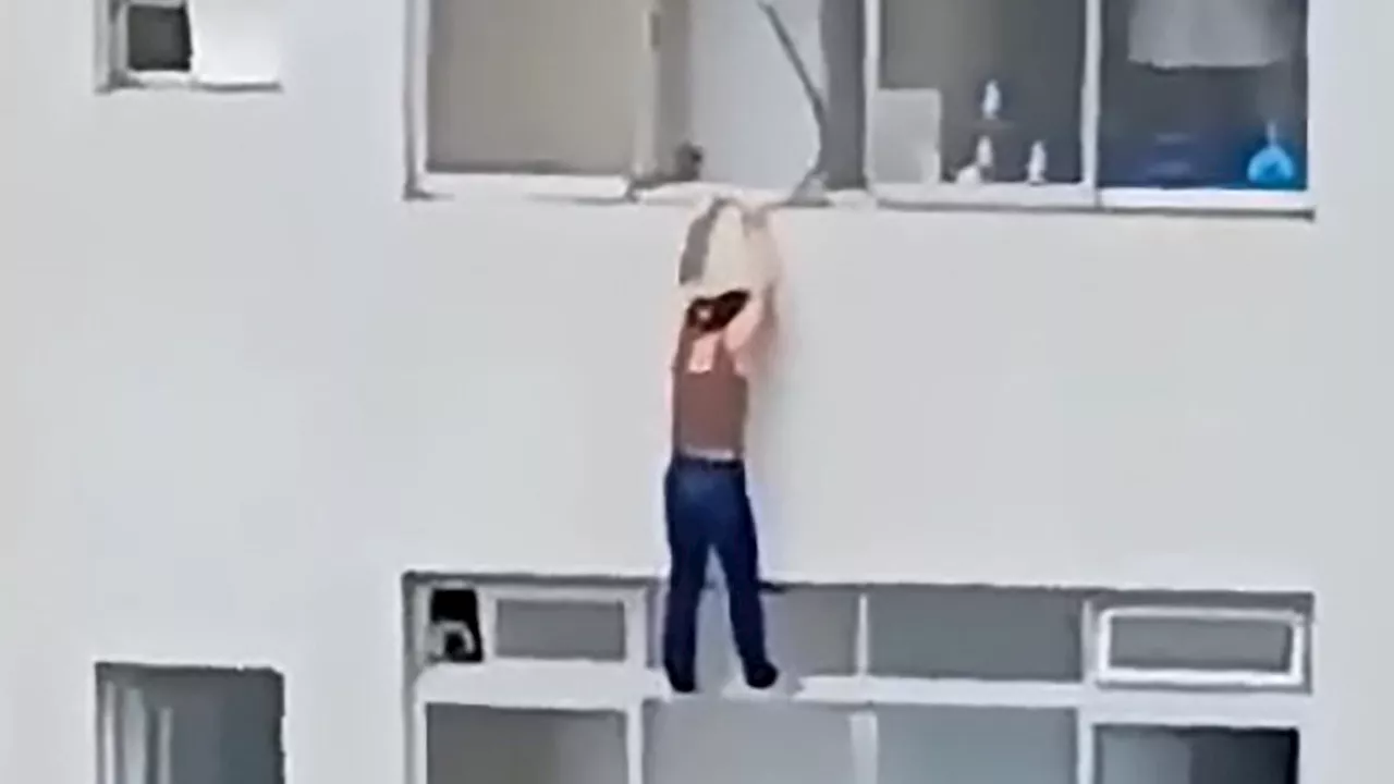 Terrifying moment cleaner dangles from 16th-floor window by fingertips