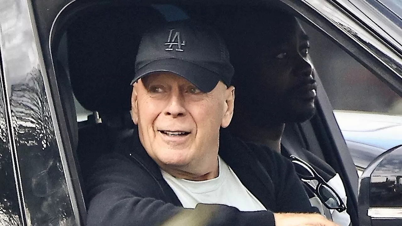 Bruce Willis smiles and dons Dodgers cap on drive with bodyguard in LA amid aphasia and dementia...