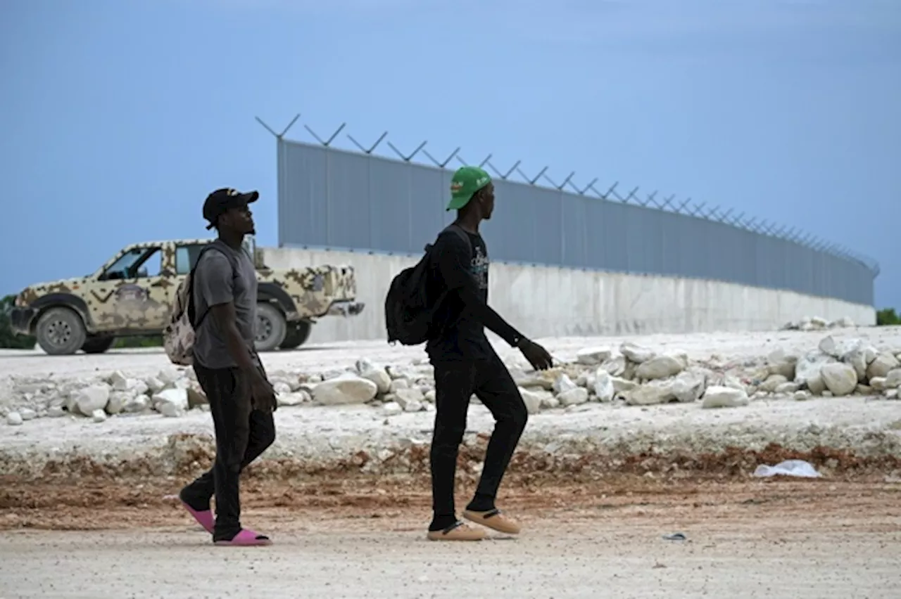 Migranti haitiani davanti al muro in costruzione al confine tra Repubblica Dominicana e Haiti