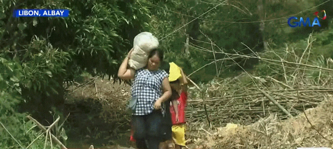 Residents walk in mud to get supplies as landslides blocked roads in Libon, Albay