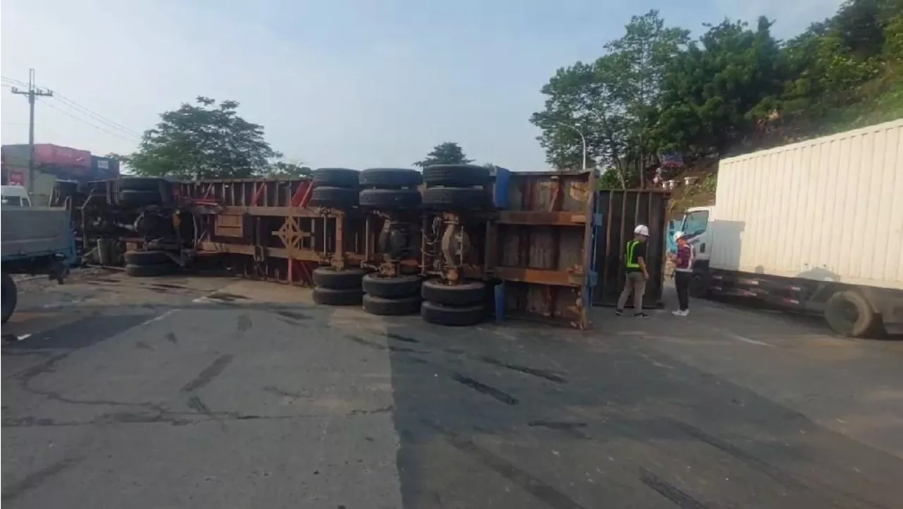 Trailer truck snarls Manila traffic after hitting barrier, tipping on its side