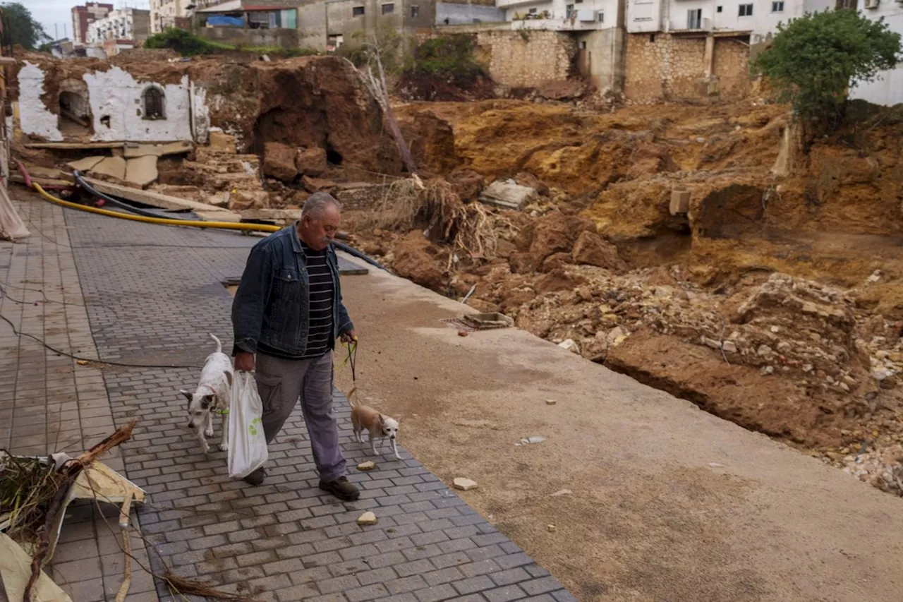 Mud-caked volunteers clean flood debris in a Spanish town as authorities struggle to respond