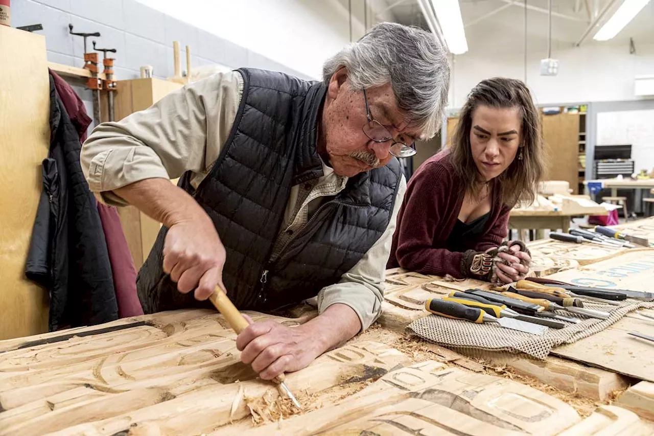 Indigenous carver Peter George refurbishes School District 57 sign with apprentice daughter