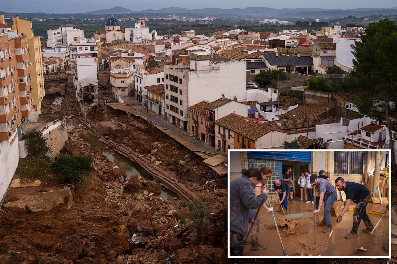 Mud-caked volunteers clean flood debris in a Spanish town as authorities struggle to respond