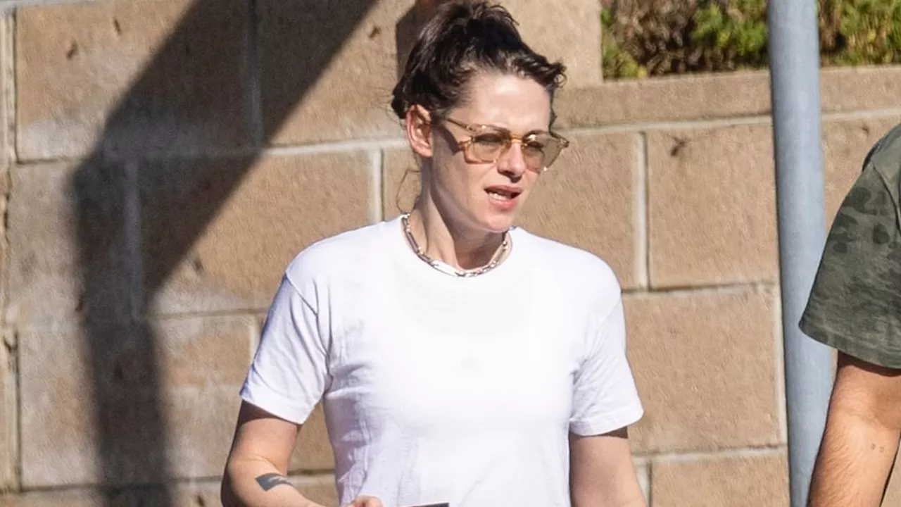 Kristen Stewart flashes her tummy in a crop top while carrying a coffee mug with a male friend in...