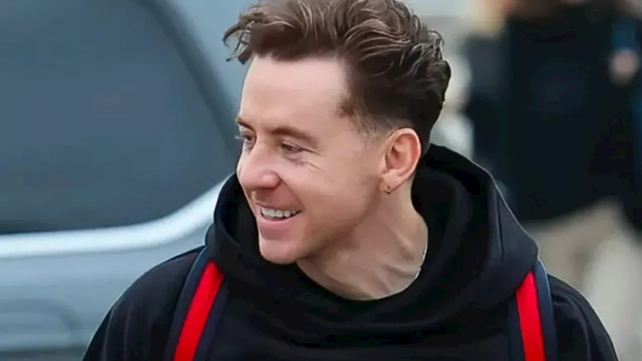 McFly’s Danny Jones can’t stop smiling as he arrives at Heathrow with Joel Dommett and Sam Thompson ahead o...