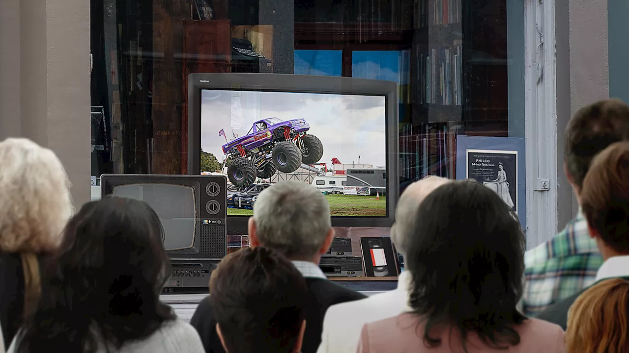 Emotional Nation Gathers Outside Main Street TV Store To Watch Monster Truck Land On Smaller Truck