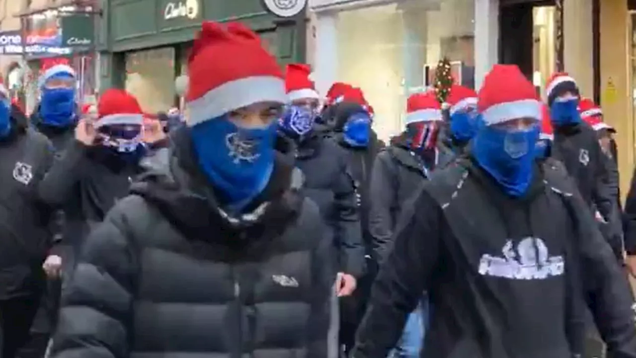 Shoppers rush for safety as Rangers fans wearing balaclavas and Santa hats charge police cordon with...