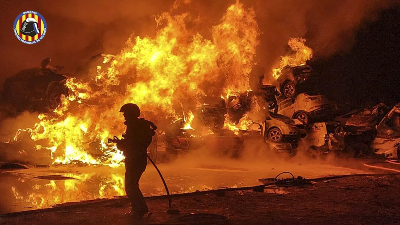 Los bomberos extinguen un incendio en un terreno con vehículos amontonados tras la DANA en Catarroja