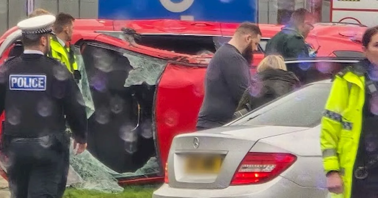 Main road closed as car flips on its side after crash