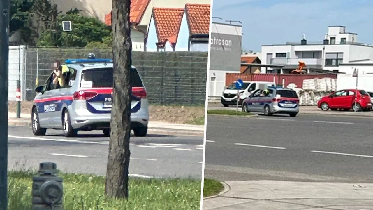 Polizist in Dienstauto hält Pistole aus dem Fenster