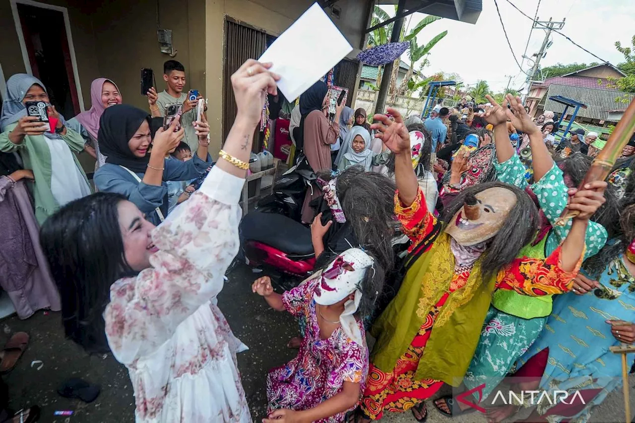 Warga Memberikan Saweran untuk Anggota Perkumpulan Rumah Menapo yang Mengenakan Topeng Labu