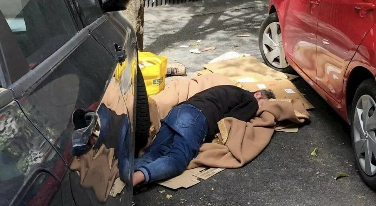 Roma, un uomo dorme avvolto nelle coperte tra le auto (e l’indifferenza dei passanti): la denuncia dei residen