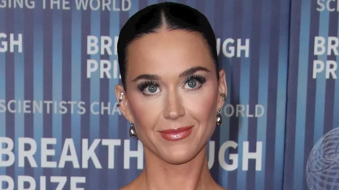 Katy Perry glams up in an elegant black dress as she lovingly cozies up to fiance Orlando Bloom at...