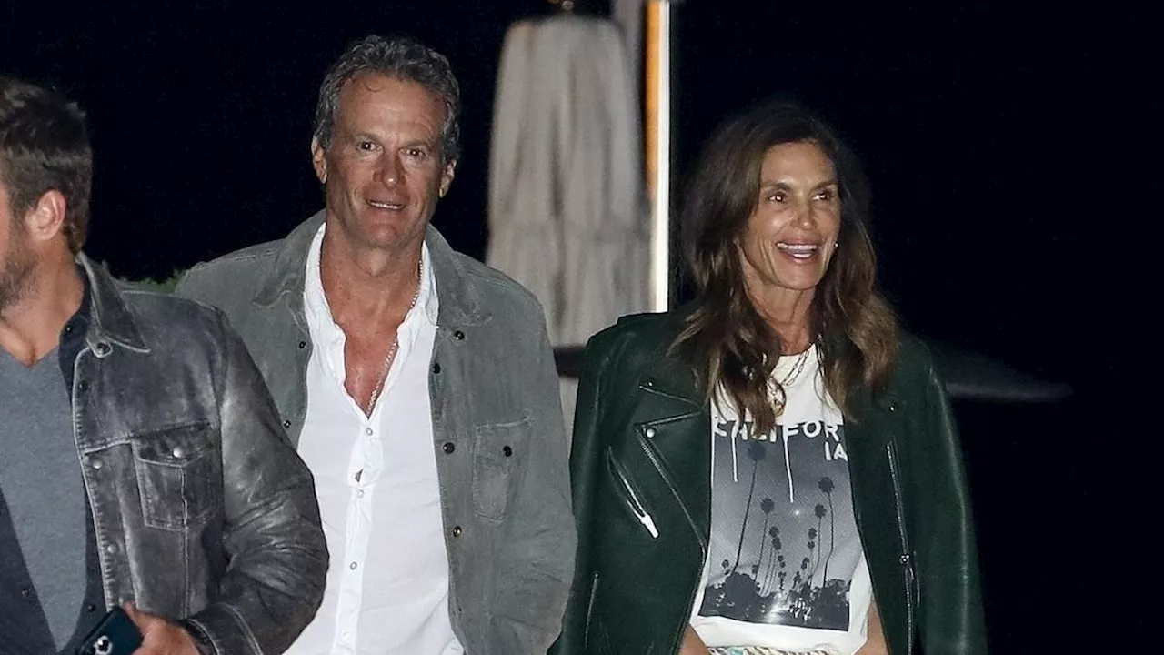 Cindy Crawford is effortlessly chic in arty skirt and emerald green leather jacket for dinner at...